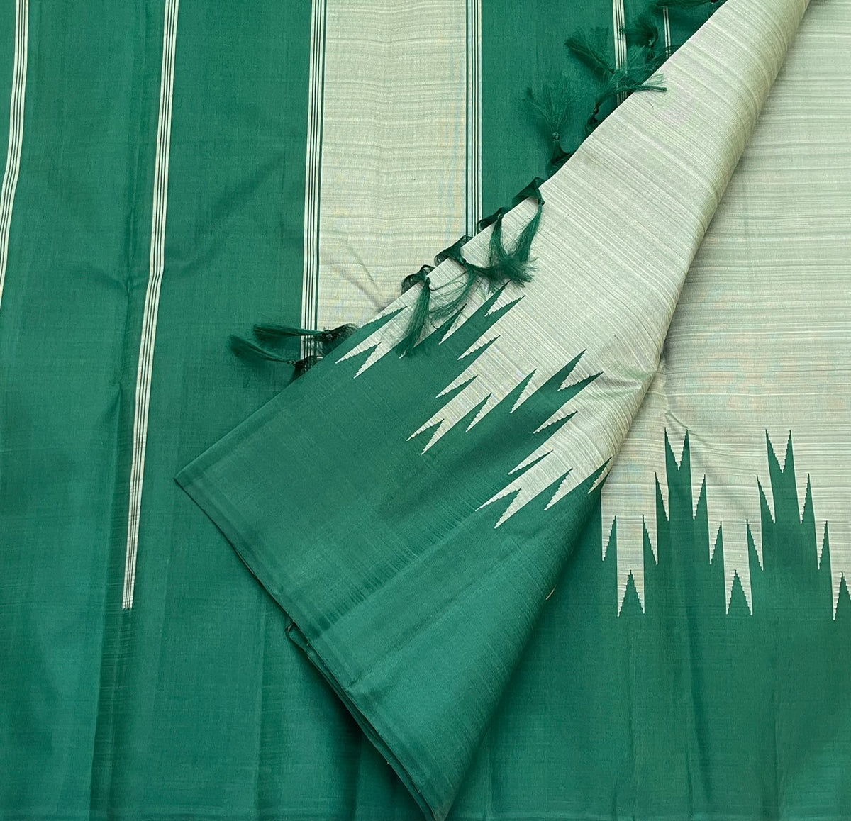 Handwoven emerald-green Kanchipuram silk saree featuring pale misty-sage body, traditional Thazampoo Reku Korvai forms and a green pallu with fine woven lines.