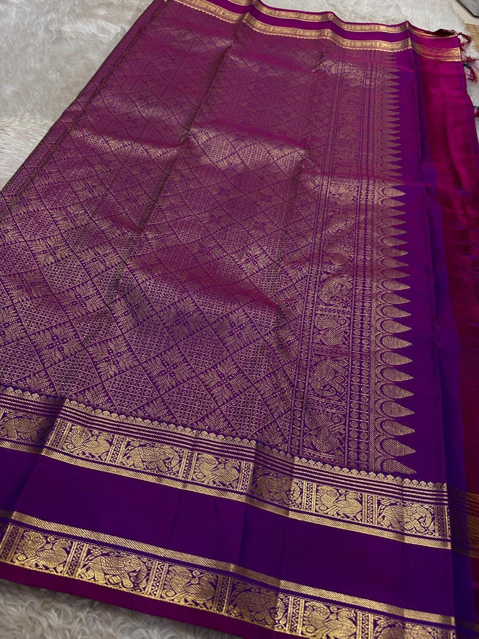 Purple saree with gold border on a gray background