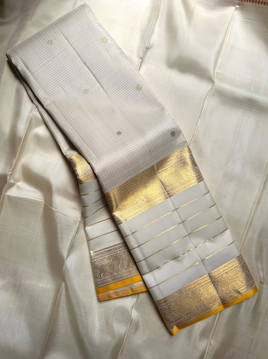 Kiran ivory whiteb oosi kattam  ✨ – ivory and gold  Kanchipuram Pure Silk Saree
Korvai Gold Zari Border with Elephant & Floral Motifs
Body Woven in Zari Kattam Checks with Scattered Gold Buttas
Grand Zari Brocade Pallu | Silk Mark Certified |