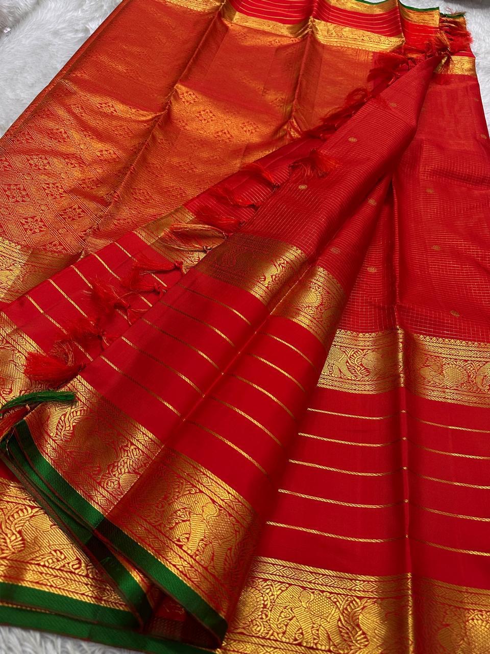 Open view of red Kanchipuram silk saree with tasselled pallu, horizontal gold zari lines and ornate elephant border with green selvedge.