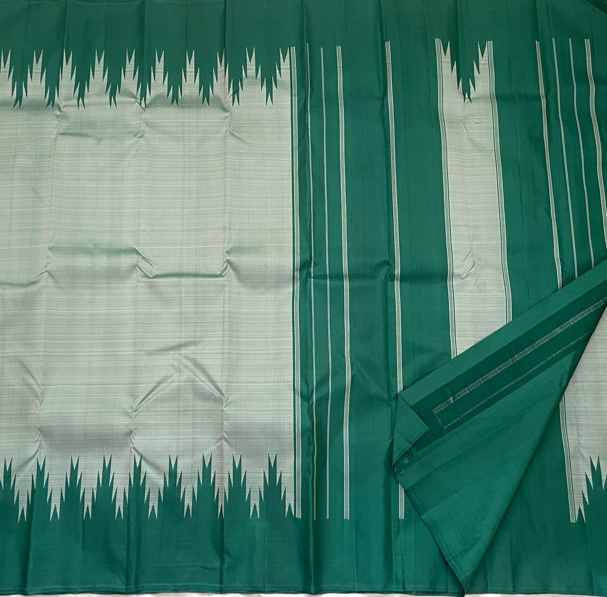Traditional Kanchipuram Thazampoo Reku Korvai border with elongated emerald-green triangular forms against pale sage silk.
