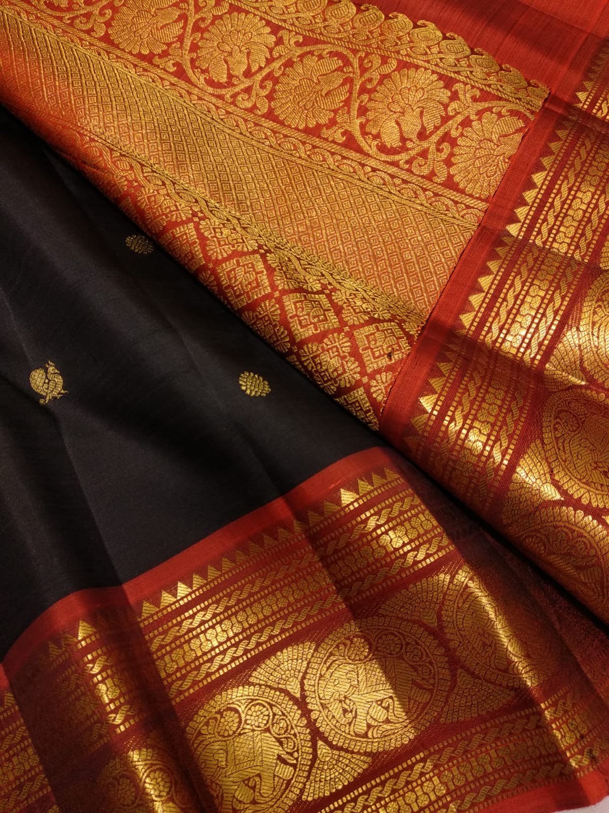 Deep black pure silk Kanchipuram saree with mayil chakram butta and traditional gold zari border