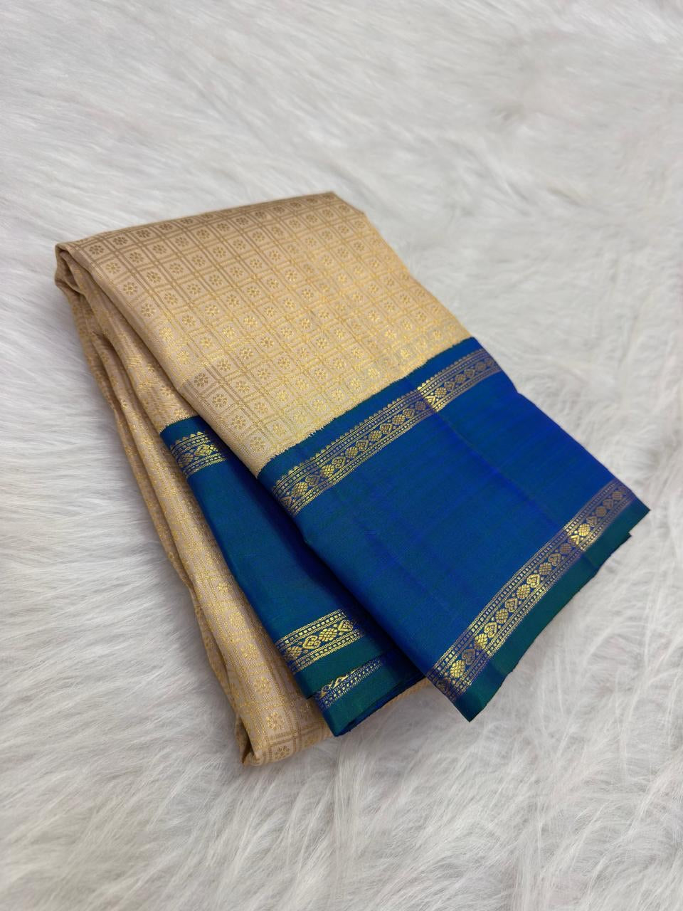 Close view of the peacock blue-green shot silk Kai Korvai border with alternating Kamalam and Kolam Suzhi gold zari bands.