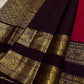 A regal  shot tomato red pink Kanchipuram silk saree features elegant chakram and mayil gold zari buttas woven across the body. Brown contrast rettapet border and Pallu vanasringaram details