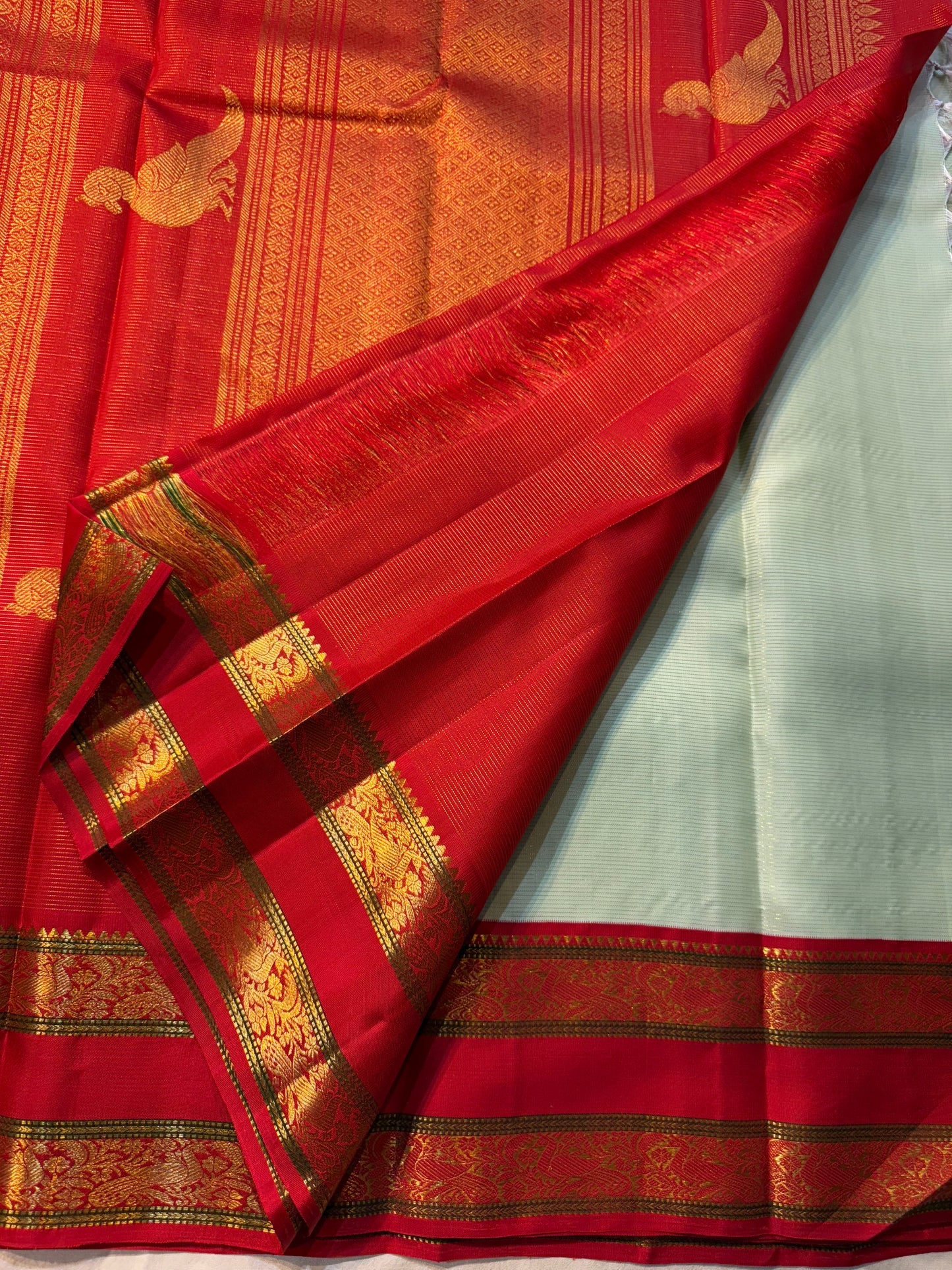 Scarlet Mist ✨ – Pastel Mint Vairaoosi Kanchipuram Pure Silk Saree
Korvai Scarlet-Red Border with Rich Zari Vines & Green Selvedge
Grand Red Pallu with Traditional Bird Buttas & Brocade Panels
Contrast Red Blouse fabric