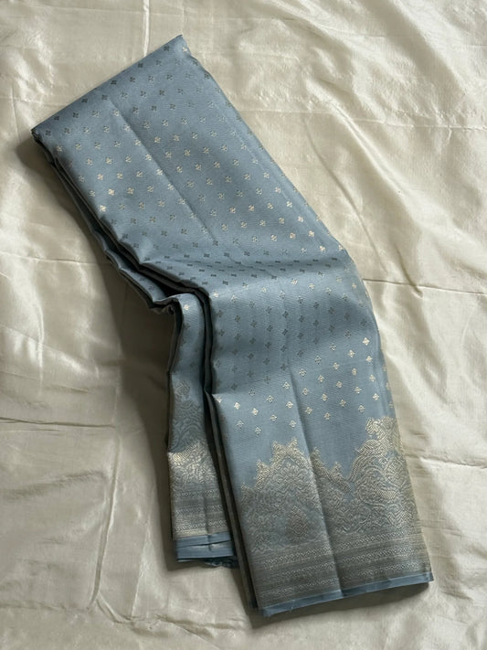 Chamomile — Kanchipuram Pure Silk

Pale gray-blue body with silver roopa buttas all over

Temple gopuram-inspired zari borders in luminous silver

Rich silver brocade pallu with intricate detailing

Silk Mark Certified • Free Shipping within USA