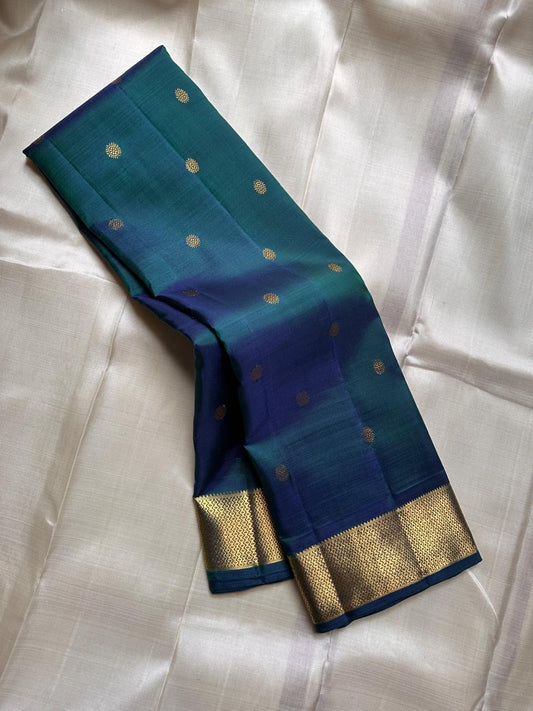Draped peacock teal and deep blue Kanchipuram silk with scattered gold zari buttas and antique-gold zari border