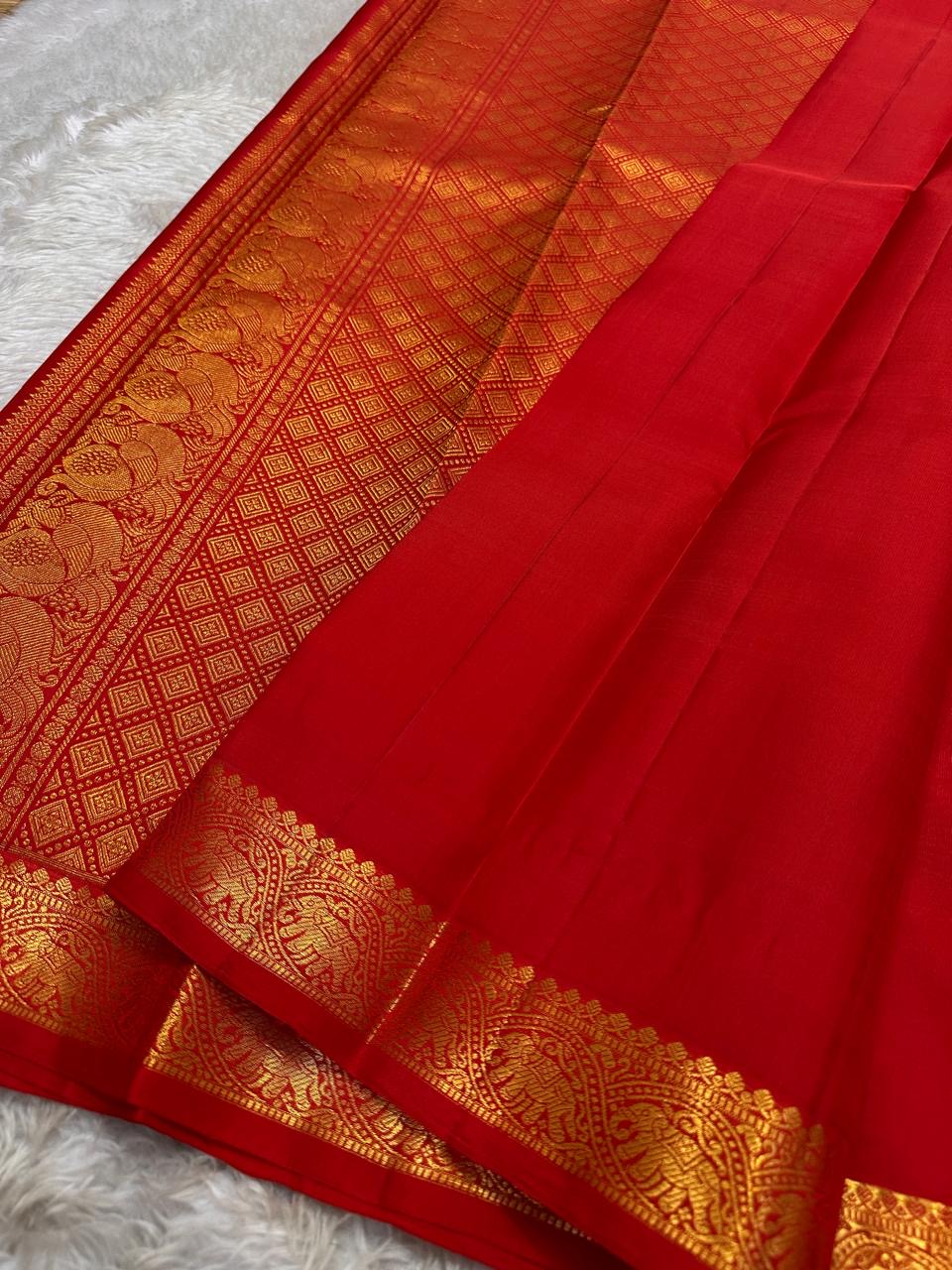 Mahima –red
A luminous red pure silk Kanchipuram drape adorned with delicate baby  kamalam buttas. The petite border features muthu seer and zari-woven elephants with floral vines. Its grand pallu showcases annams, golden grids, and Rudhraksham seer.