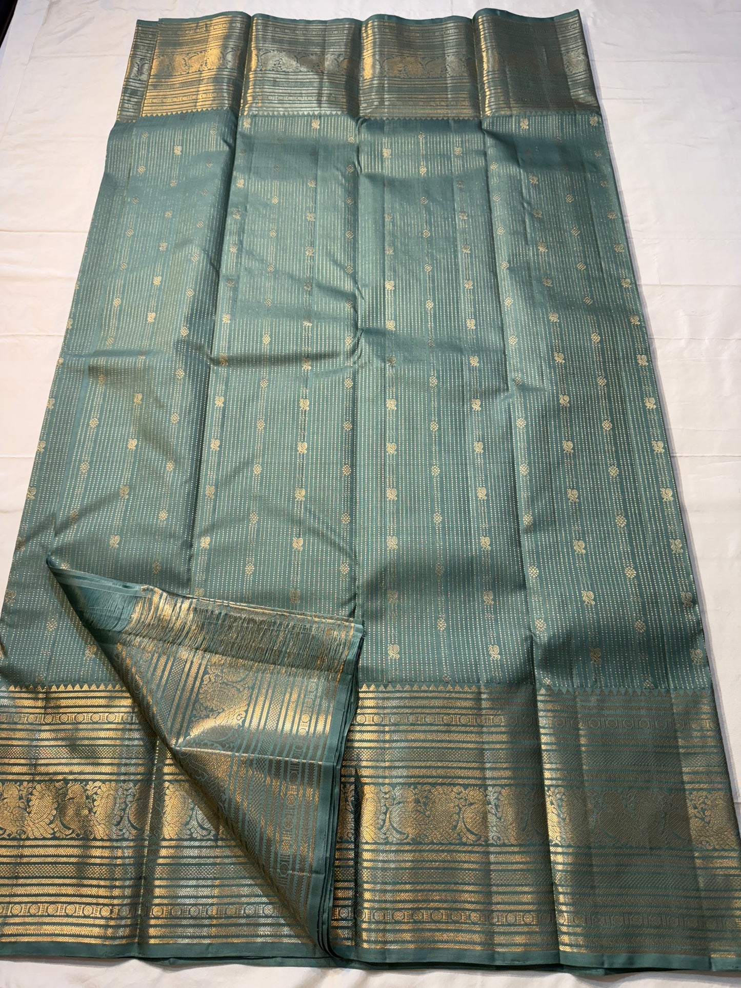 Muted sea-jade/duck-egg green body with fine oosi (pin) stripes

All-over tiny rosette/coin buttas for a soft shimmer

Silk Mark Certified | Free Shipping within USA | Ships in Two Weeks. Blouse Stitching ($30)