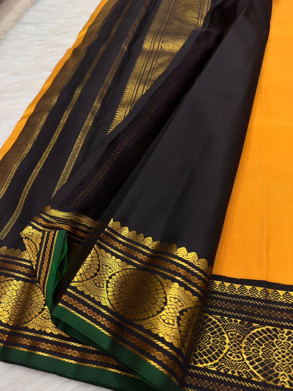 Turmeric yellow Kanchi Pattu silk body with needle-fine vertical Oosi Vaanam zari lines and small gold zari buttas.