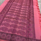 Full view of paisley pallu field with wide dark border on a pink pure Kanchipuram silk saree laid on a rug