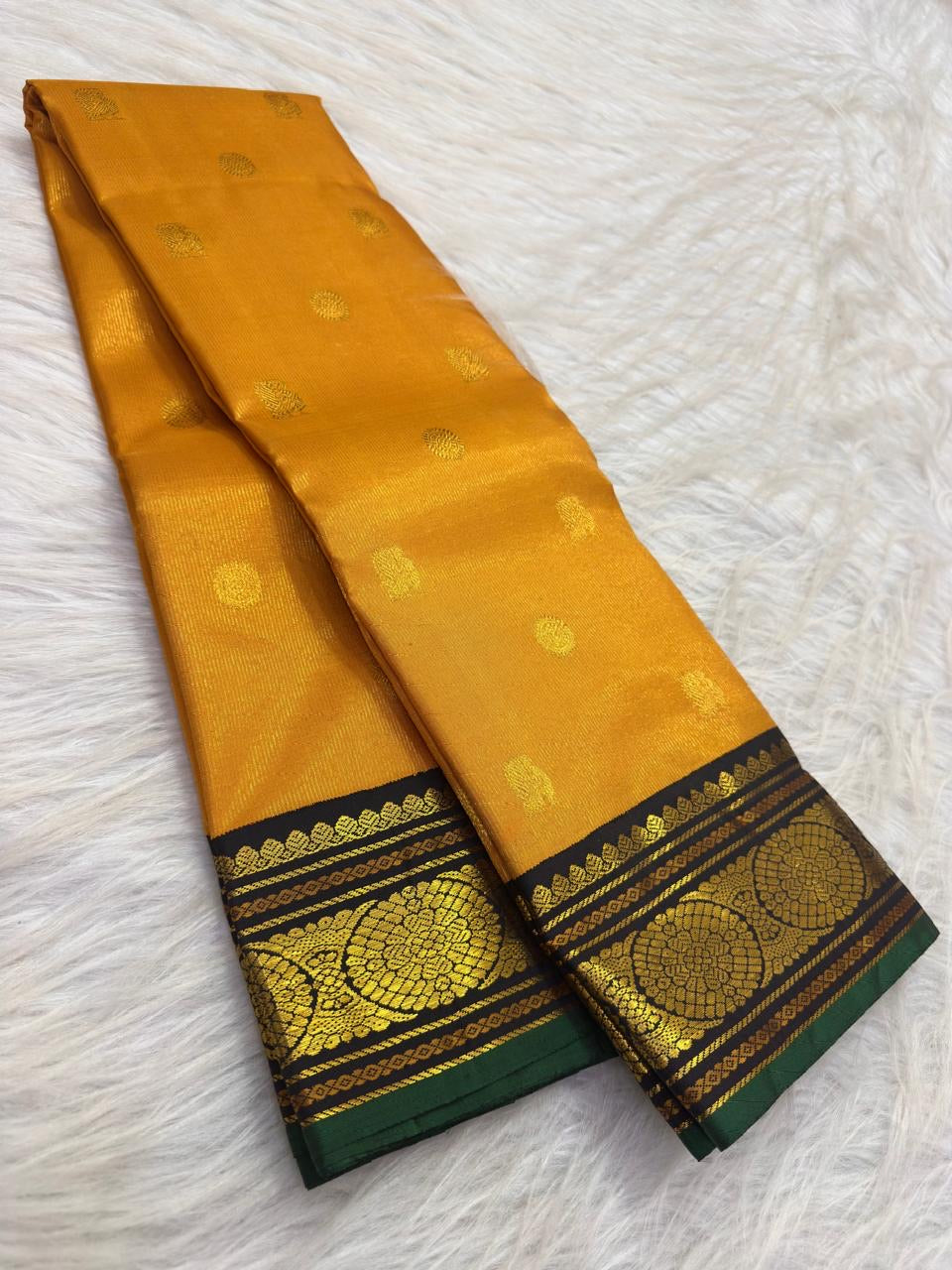 Black Kanchipuram pallu with twin vertical gold zari Kamalam bands, fine traditional motif stripes and turmeric tassels.