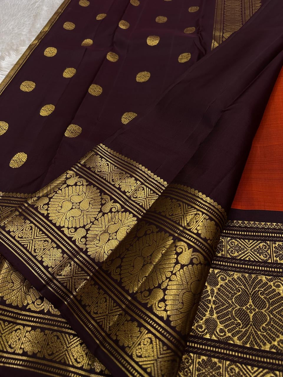 Rust Orange Coffee Brown — Flower Butta | Pure Kanchipuram Silk Saree
Rust-orange body with dainty zari-woven flower buttas and grand coffee-brown korvai borders rich in antique-gold floral medallions.
Silk Mark Certified • Blouse Stitching Available ($30