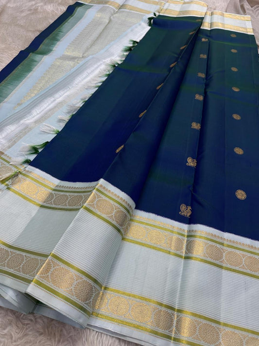 Mayil Kazhuthu ✨ – Peacock’s Neck Kanchipuram Pure Silk Saree
Korvai Royal-Purple Border with Peacock & Floral Zari Vines
Body Embellished with Gold Kamalam (Lotus) Buttas
Grand Gold Zari Pallu with Traditional Motifs & Hand-knotted Tassels
Silk Mark