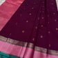 A regal magenta silk with intricate  zari buttas scattered delicately across the body. The border is a stunning blend of soft pink and teal, featuring fine gold silver  zari weaving and temple motifs