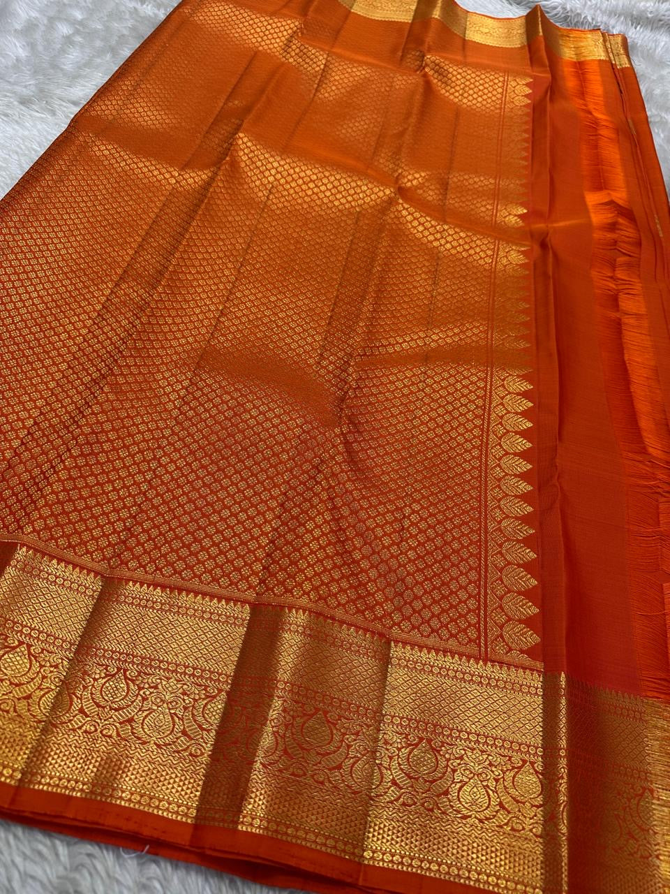 Red Kanchipuram silk saree with gold peacock buttas and traditional gold zari border shown fully opened.
