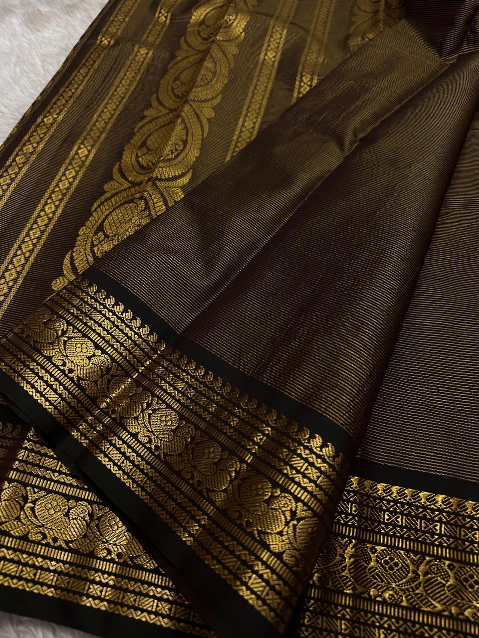 Kohl Swarna — silk mark certified lightweight saree 
Deep kohl brown body with fine pinstripes and gold rosette buttas, framed by antique-gold zari borders and grand paisley brocade pallu• free shipping eithin usa  two weeks
