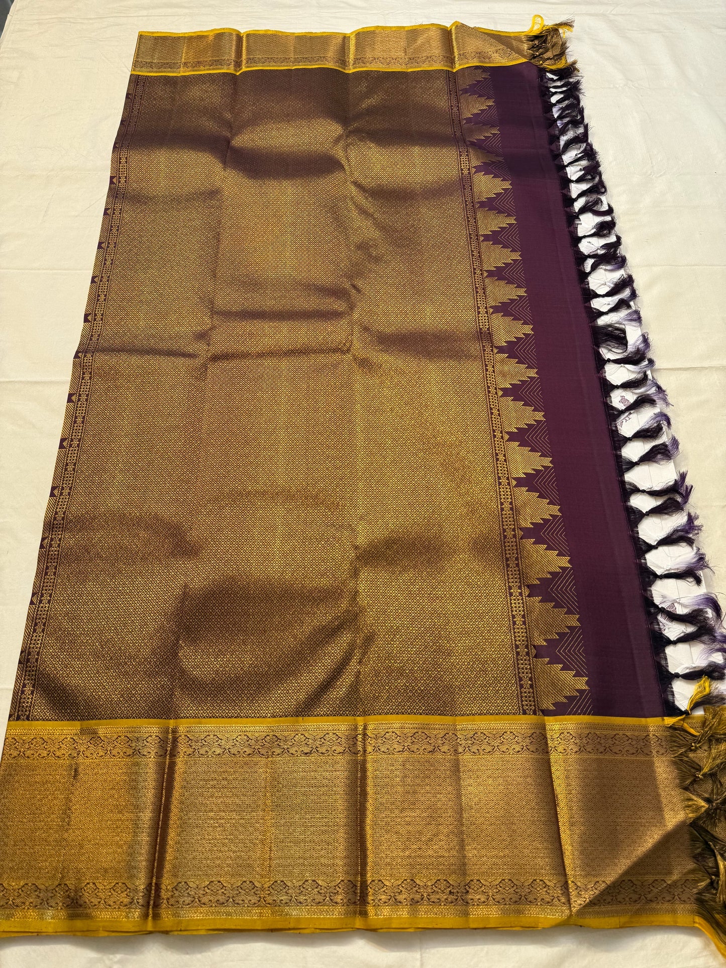 Full pallu layout of plum and gold Kanchipuram silk saree with traditional reku-style edging and tassels