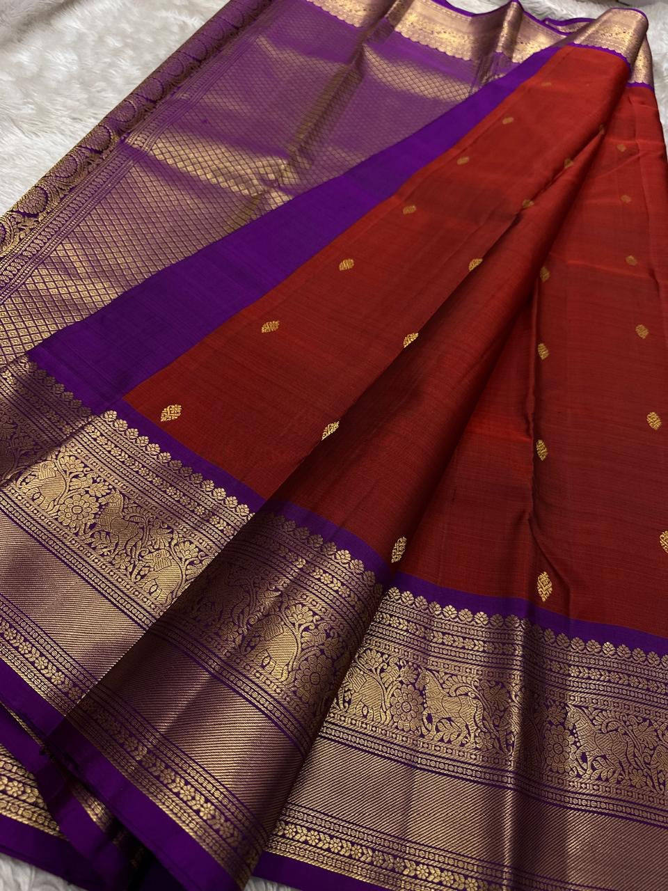 Kumkuma kokilam — Pure Kanchipuram Silk Saree
Kumkum red body with antique gold zari buttas & royal purple contrast border
Silk Mark Certified • Blouse Stitching Available ($30) • Free Shipping within USA • Ships in Two Weeks