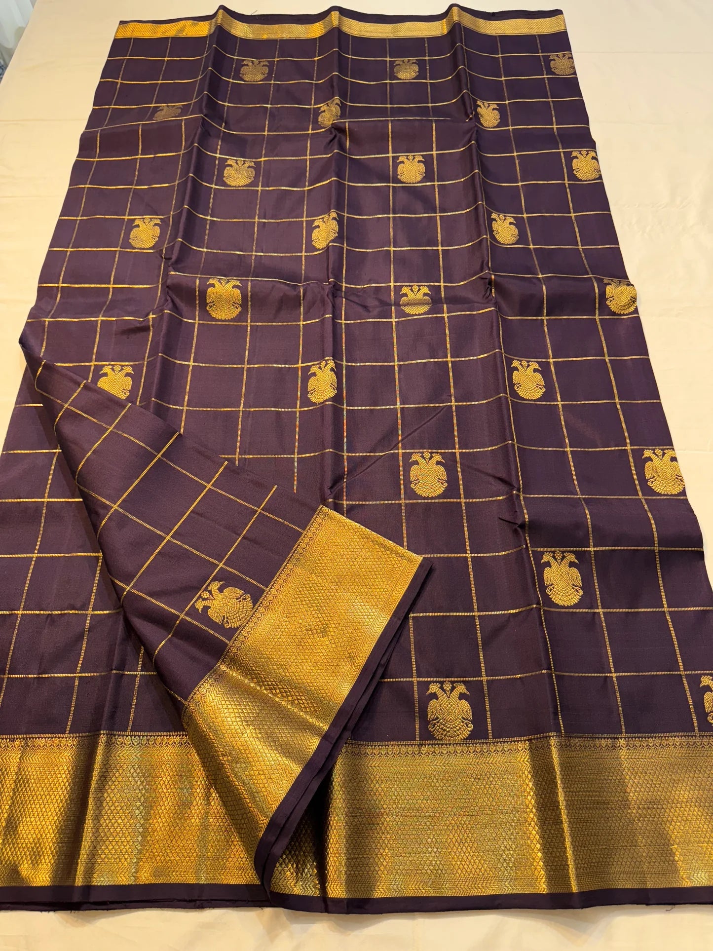 Plum Zari Kattam — Pure Kanchipuram Silk Saree
Rich plum body with gold kattam grid & Gandaberunda buttas ✨
Antique-gold brocade border & grand zari pallu • Silk Mark Certified • Free Shipping within USA • Ships in Two Weeks