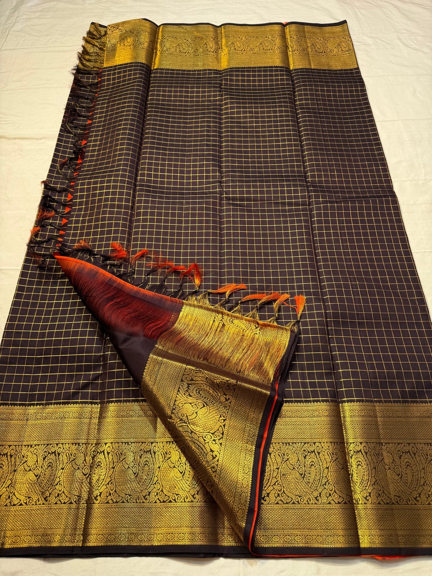 Mathura Layam — Pure Silk Kanchipuram Saree
Deep espresso brown with gold varisaipet checks & peacock zari border
Vermilion red vaira-kattam pallu | Silk Mark Certified | Ships in 2 Weeks | Free USA Shipping