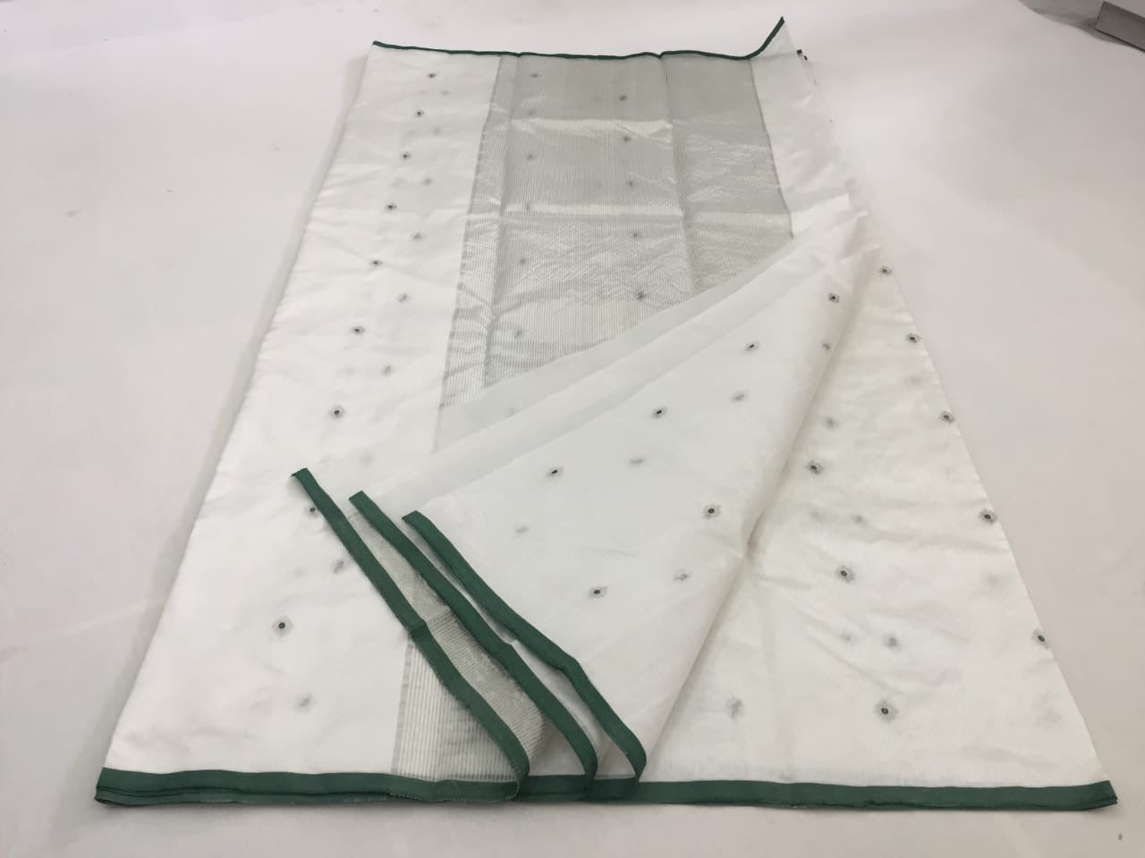 Draped in ivery white , this pure silk Chanderi saree glows with a gentle sheen and graceful vertical zari lines. Delicate diamond meenakari motifs and finely woven borders lend a touch of tradition, while the contrast green selvedge adds a subtle edging