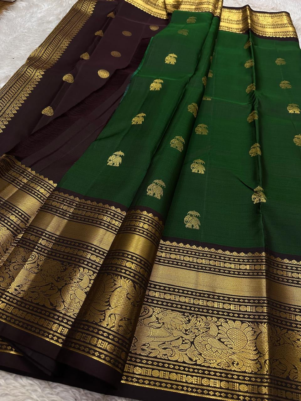 Emerald Green Elephant Butta — Pure Kanchipuram Silk Saree
Emerald green body with antique-gold zari elephant buttas and grand coffee-brown korvai borders featuring yali–mayil motifs.
Silk Mark Certified • Blouse Stitching Available ($30) • Free Shipping