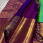 This pure silk Kanchipuram saree features a radiant shot color blend of green, gold, and blue, adorned with delicate zari buttas. A regal royal purple rettapet border and an elaborate peacock motif pallu complete this timeless drape — perfect for festive