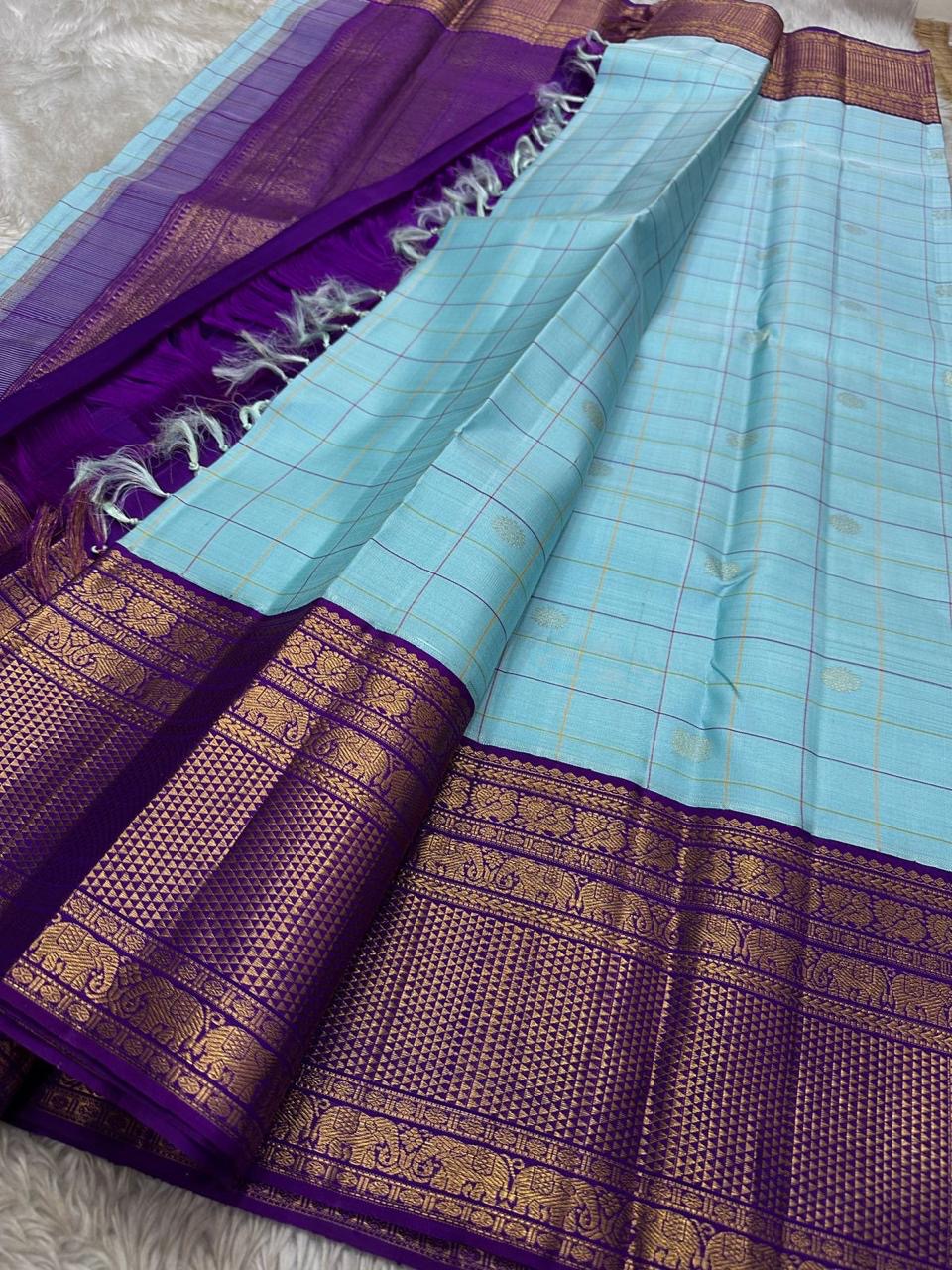 Aakasa Kattam — Pure Kanchipuram Silk Saree
Sky-aqua body with fine kattam checks in lemon and violet, adorned with silver-zari paisley buttas and contrast purple brocade borders.
Silk Mark Certified • Free Shipping within USA • Dispatch in 1 Week • Ships