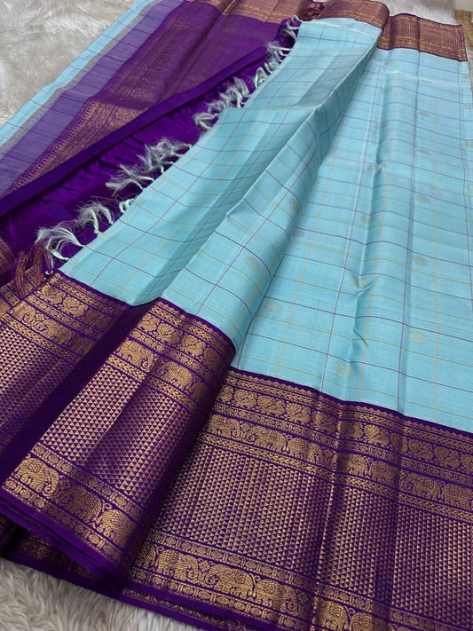 Aakasa Kattam — Pure Kanchipuram Silk Saree
Sky-aqua body with fine kattam checks in lemon and violet, adorned with silver-zari paisley buttas and contrast purple brocade borders.
Silk Mark Certified • Free Shipping within USA • Dispatch in 1 Week • Ships