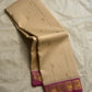 Cream silk saree draped loosely, showing scattered gold buttas and a magenta border with gold zari woven detailing.