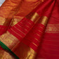 Close-up of red Kanchipuram silk saree pallu featuring dense gold zari weaving, traditional motifs and striped body.