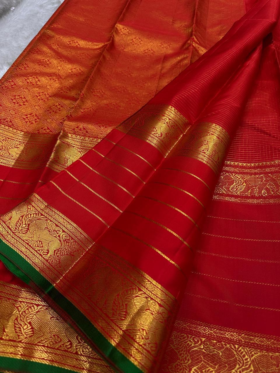 Close-up of red Kanchipuram silk saree pallu featuring dense gold zari weaving, traditional motifs and striped body.