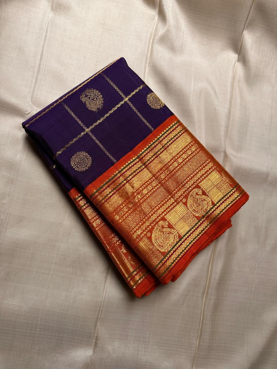 Raga Priya ✨ – Pure Kanchipuram Silk Saree
Royal Purple Body with Zari Kattam & Mayil Chakram Buttas
Sunset Orange Korvai Border in Neli Vanki Zari Pattern
Grand Orange Brocade Pallu with Intricate Weaves
Silk Mark Certified | Fall & Pico Done |