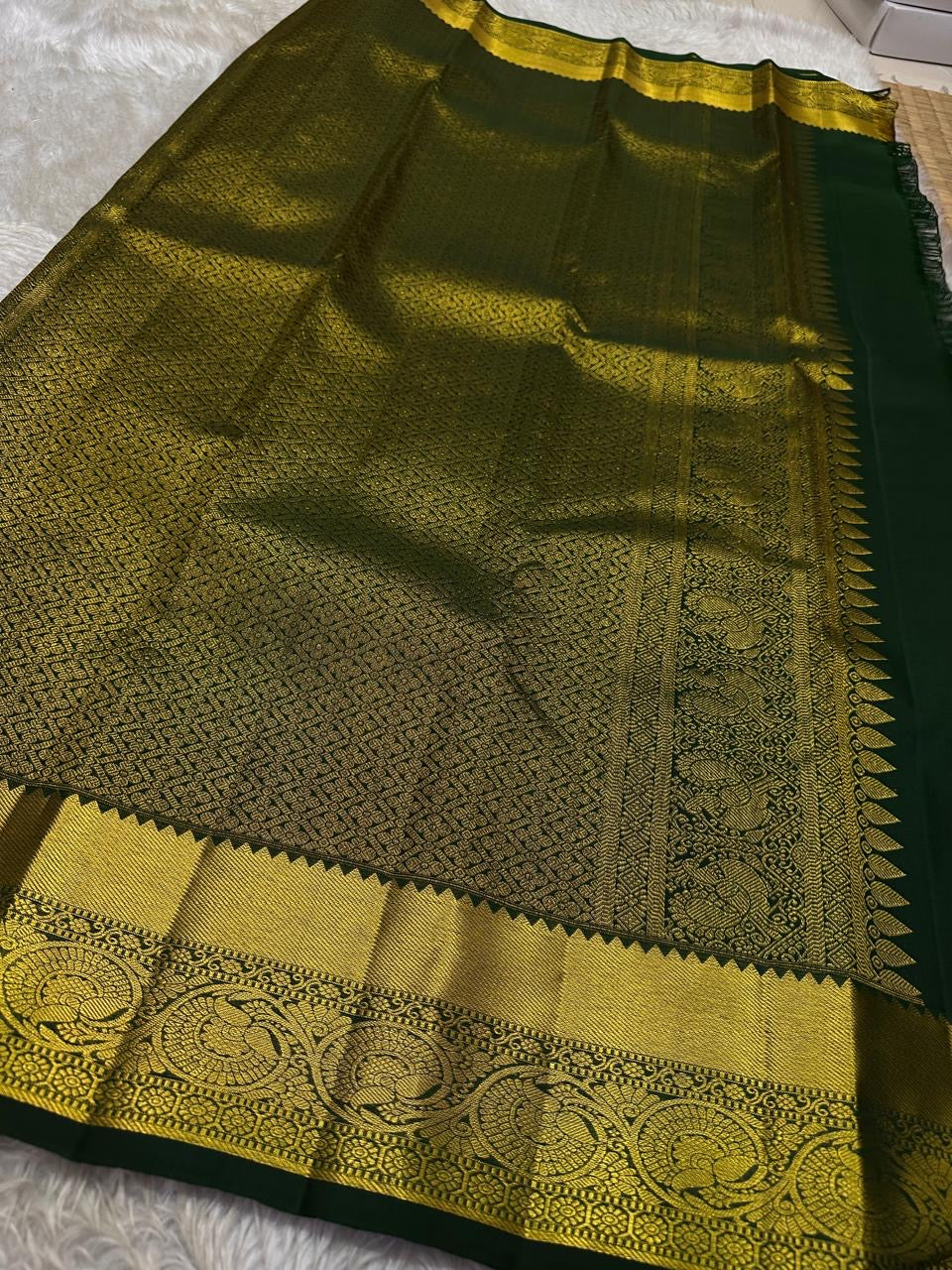 Agnika – Green Kanchipuram Silk Saree with Mayil Chakram Butta
Fiery and regal, Agnika features a rich green silk body with intricate Mayil Chakram (peacock) motifs and a shimmering zari border—an elegant ode to South Indian tradition.