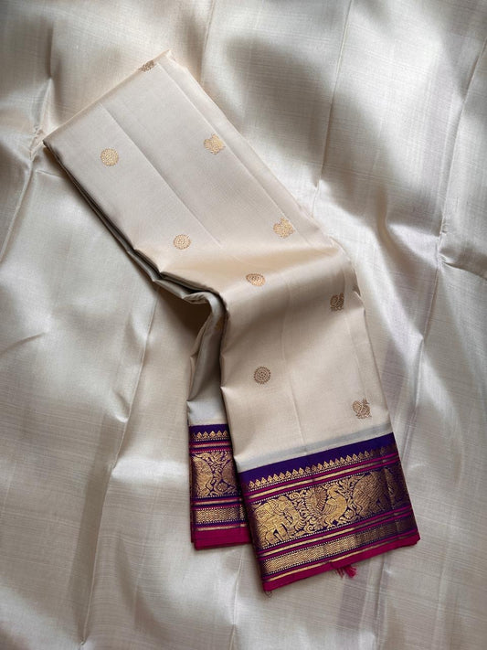 ⸻

Ivory Glow ✨ – Pure Kanchipuram Silk Saree in Ivory

Korvai Royal-Purple Border with Elephant & Peacock Zari Panels; Magenta Selvedge
Body with Gold Coin & Paisley Buttas
Grand Royal-Purple Brocade Zari Pallu with Hand-knotted Tassels