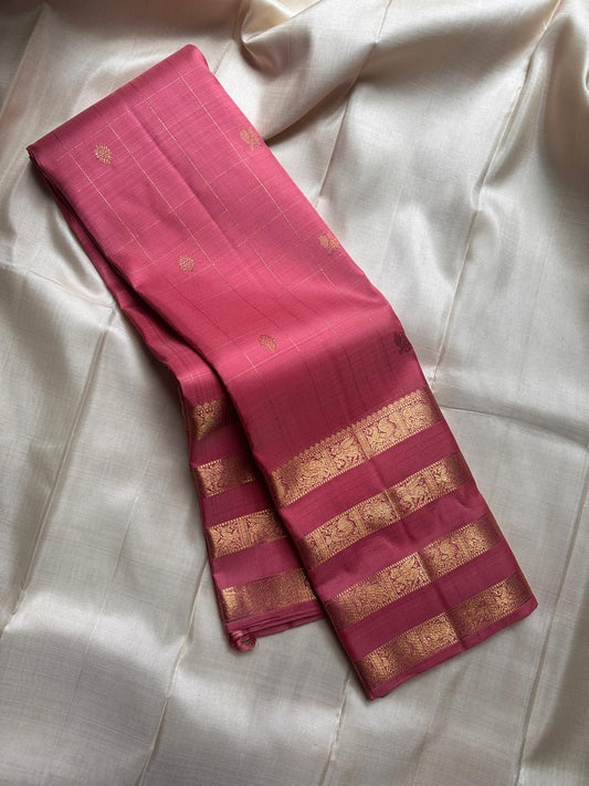 vasantham  pink – Handwoven Kanchipuram Silk Saree
A poem in pink silk. The body glows in a serene rose pink, softly accented by delicate gold vertical lines and dainty gold zari buttas that glint like little blessings.
