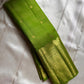 A radiant parrot green Kanchipuram silk saree that dazzles. The body features a delicate grid-like zari weave with small gold buttas scattered. The rich gold zari pallu stands out with grand temple-inspired arches and intricate motifs.