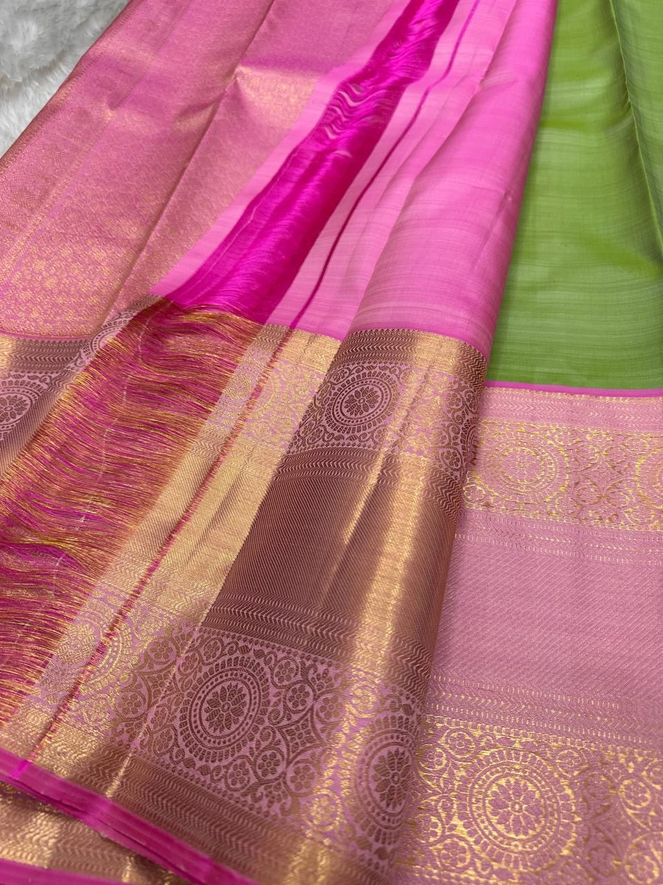 Pink zari woven pallu with gold detailing and tassels, closeup view