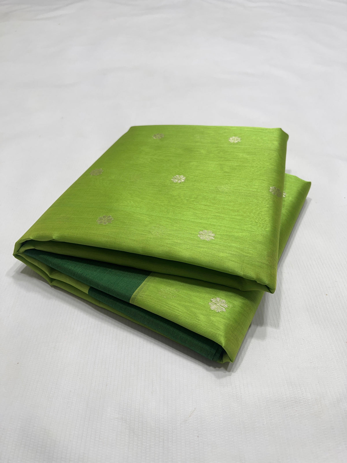Folded Parrot Green Chanderi saree showing the silver floral buttas and forest green border