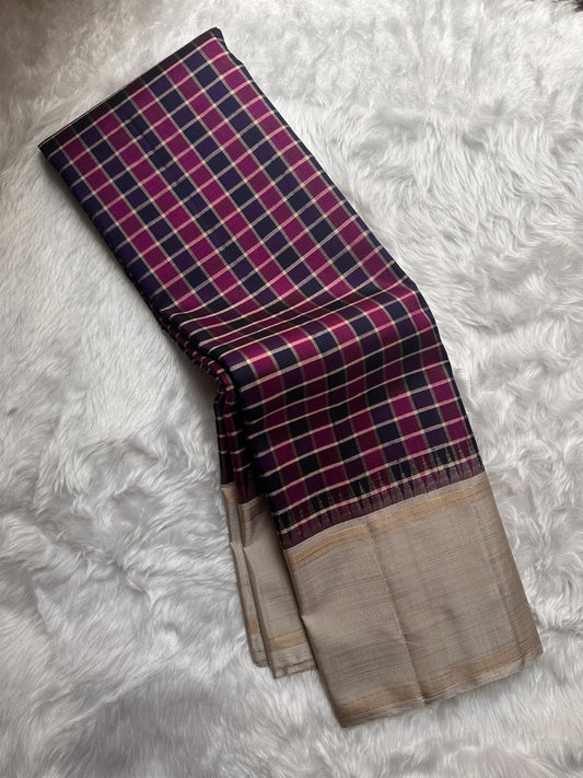 Nirai Navy - A Jewel Toned Checkered pure silk Kanchipuram saree in navy, purple, magenta, and grey checks.Accented with a soft silver-grey border and zari-striped seer pallu
Includes a silver blouse fabric with gold zari stripes