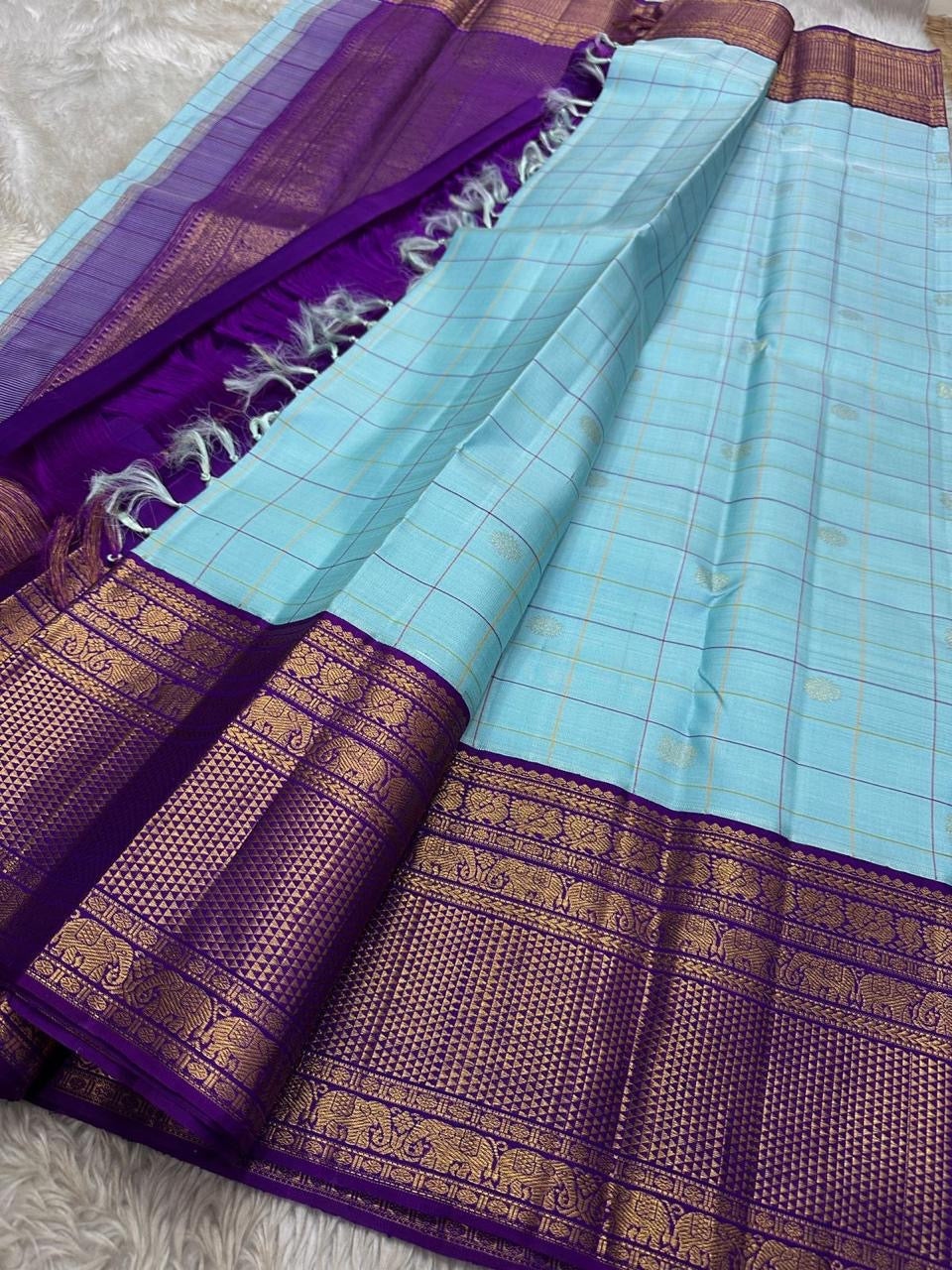 Aakasa Kattam — Pure Kanchipuram Silk Saree
Sky-aqua body with fine kattam checks in lemon and violet, adorned with silver-zari paisley buttas and contrast purple brocade borders.
Silk Mark Certified • Free Shipping within USA • Dispatch in 1 Week • Ships