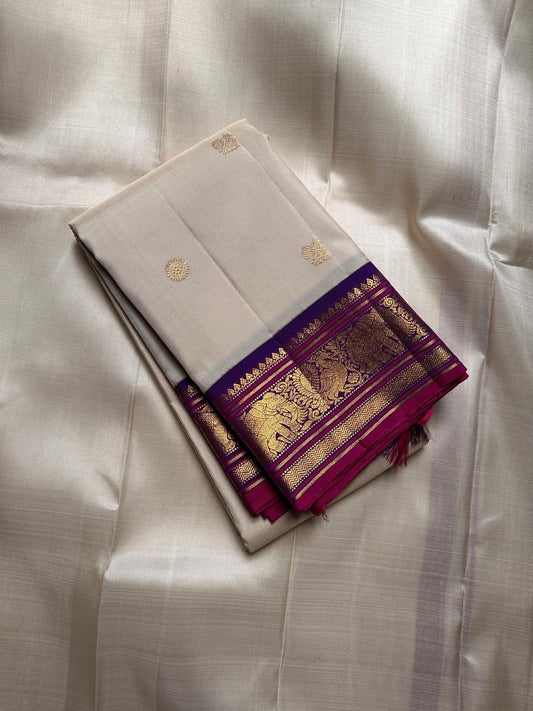 ⸻

Ivory Glow ✨ – Pure Kanchipuram Silk Saree in Ivory

Korvai Royal-Purple Border with Elephant & Peacock Zari Panels; Magenta Selvedge
Body with Gold Coin & Paisley Buttas
Grand Royal-Purple Brocade Zari Pallu with Hand-knotted Tassels