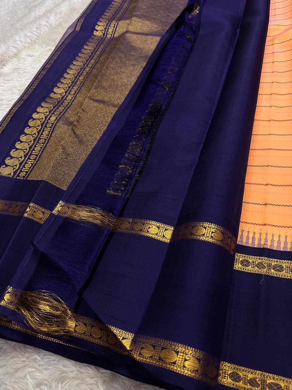 Peach Veldhari ✨ – Pure Kanchipuram Silk Saree with Royal Blue Border & Pallu

Peach-Orange Veldhari Striped Body with Subtle Green & Maroon Accents

Royal Blue Korvai Border with Intricate Gold Zari Motifs

Majestic Royal Blue Zari Brocade Pallu