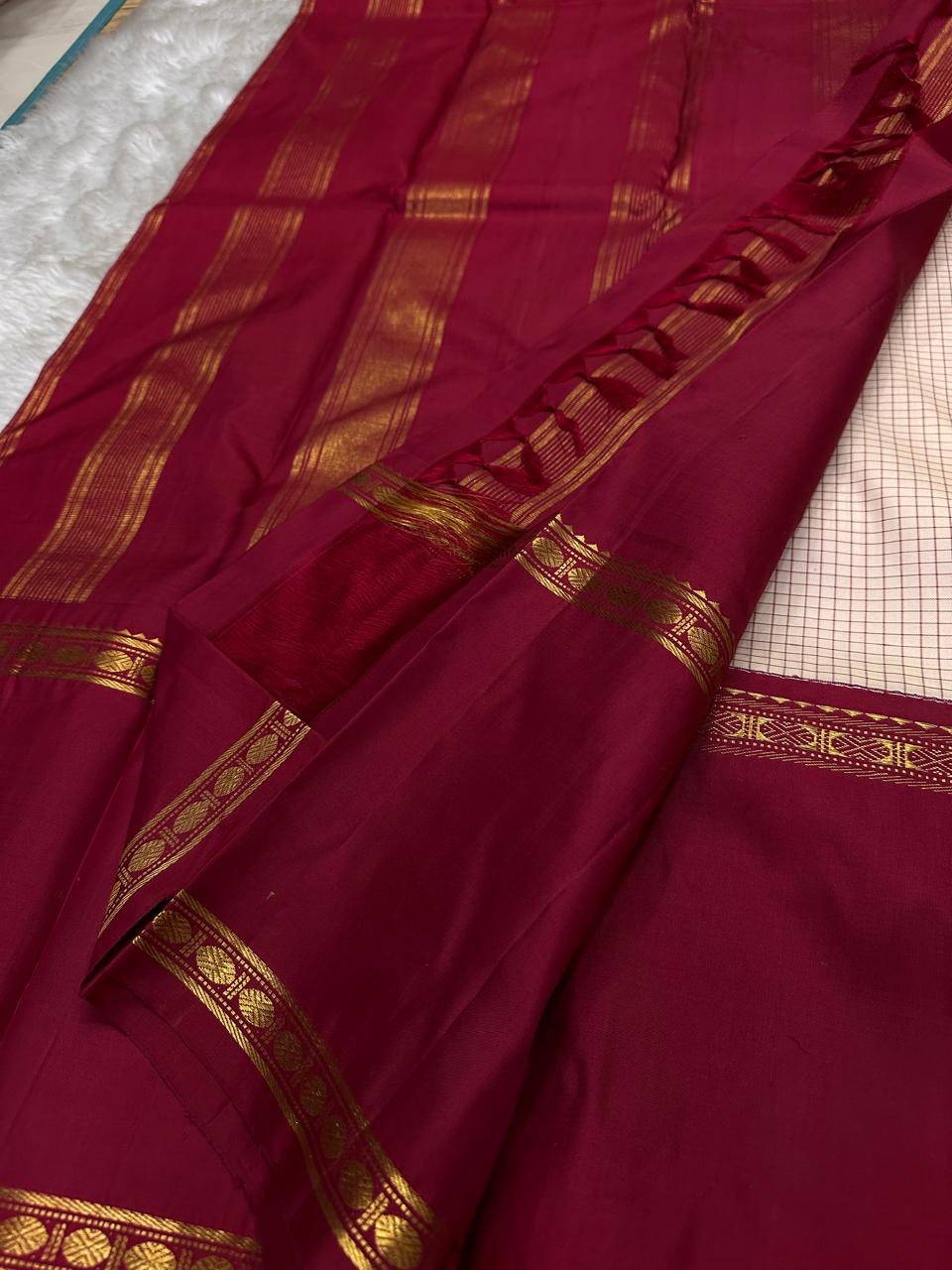 Maroon pallu close-up with gold zari lines, tassels, and rich silk sheen