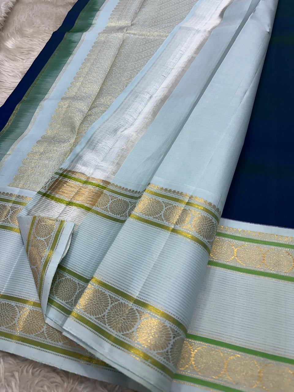 Mayil Kazhuthu ✨ – Peacock’s Neck Kanchipuram Pure Silk Saree
Korvai Royal-Purple Border with Peacock & Floral Zari Vines
Body Embellished with Gold Kamalam (Lotus) Buttas
Grand Gold Zari Pallu with Traditional Motifs & Hand-knotted Tassels
Silk Mark