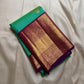This pure silk Kanchipuram saree features a radiant shot color blend of green, gold, and blue, adorned with delicate zari buttas. A regal royal purple rettapet border and an elaborate peacock motif pallu complete this timeless drape — perfect for festive