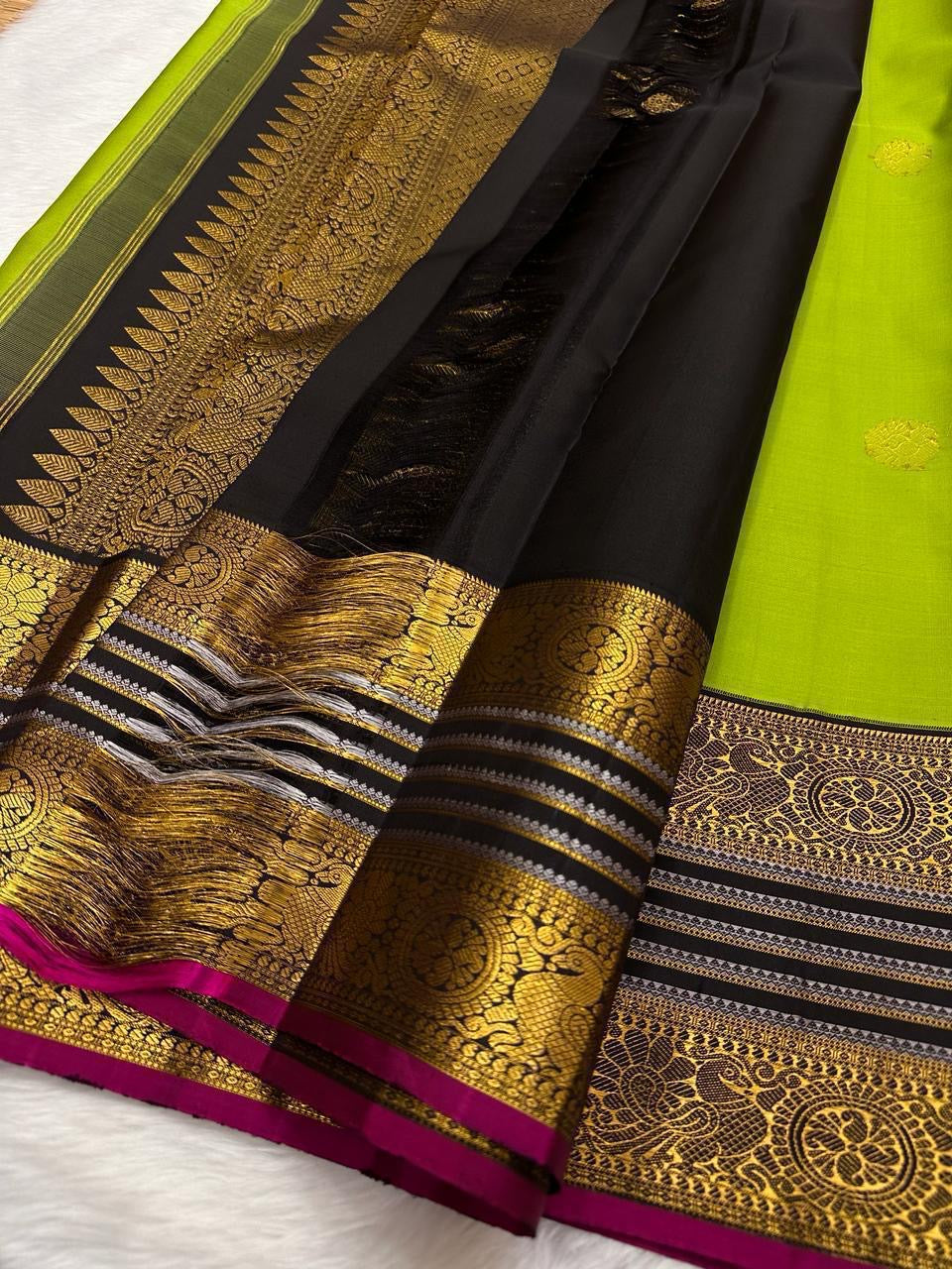 Kili Pachai — Pure Silk Kanchipuram Saree
Parrot-Green Body with Gold Buttas ✨
Black Korvai Borders with Peacock Medallions 🦚
Black Brocade Pallu • Contrast Black Blouse with Zari 🌸
Silk Mark Certified • Free Shipping within USA • Ships in Two Weeks