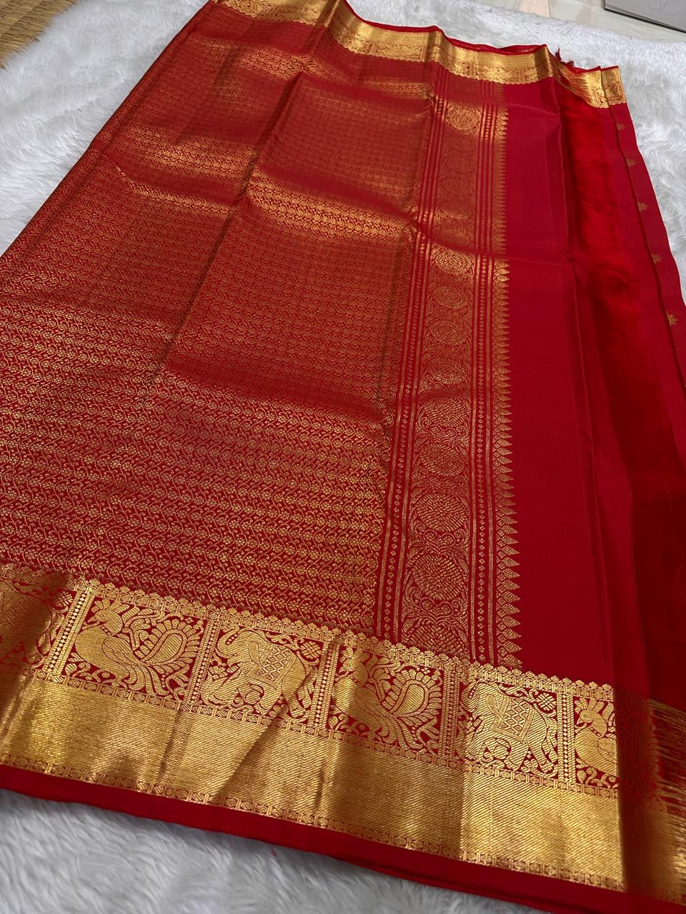 Dia ✨ – Chilli Red Pure Kanchipuram Silk Saree
Allover Gold Zari Floral Buttas on Body
Broad Elephant–Peacock (Gaja–Mayil) Zari Panel Border
Rich Red & Gold Brocade Pallu with Intricate Weaves
Silk Mark Certified | Fall & Pico Done | Blouse Stitching $30