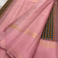 Nirai – A Madras-Inspired Kanchipuram Silk in Amber & Pastel Pink.
Woven with fine podi kattam checks in black, amber orange, and grey.
The pastel pink border with pillayar moggu detailing adds softness, with a  seer zari pallu